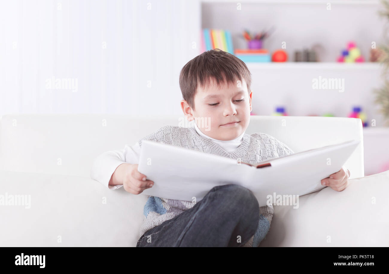 preschooler reading a book on the couch in the nursery Stock Photo Alamy