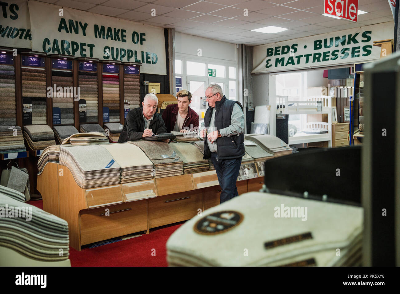 Multi-generation family business are stocking their carpet and furniture shop. Stock Photo