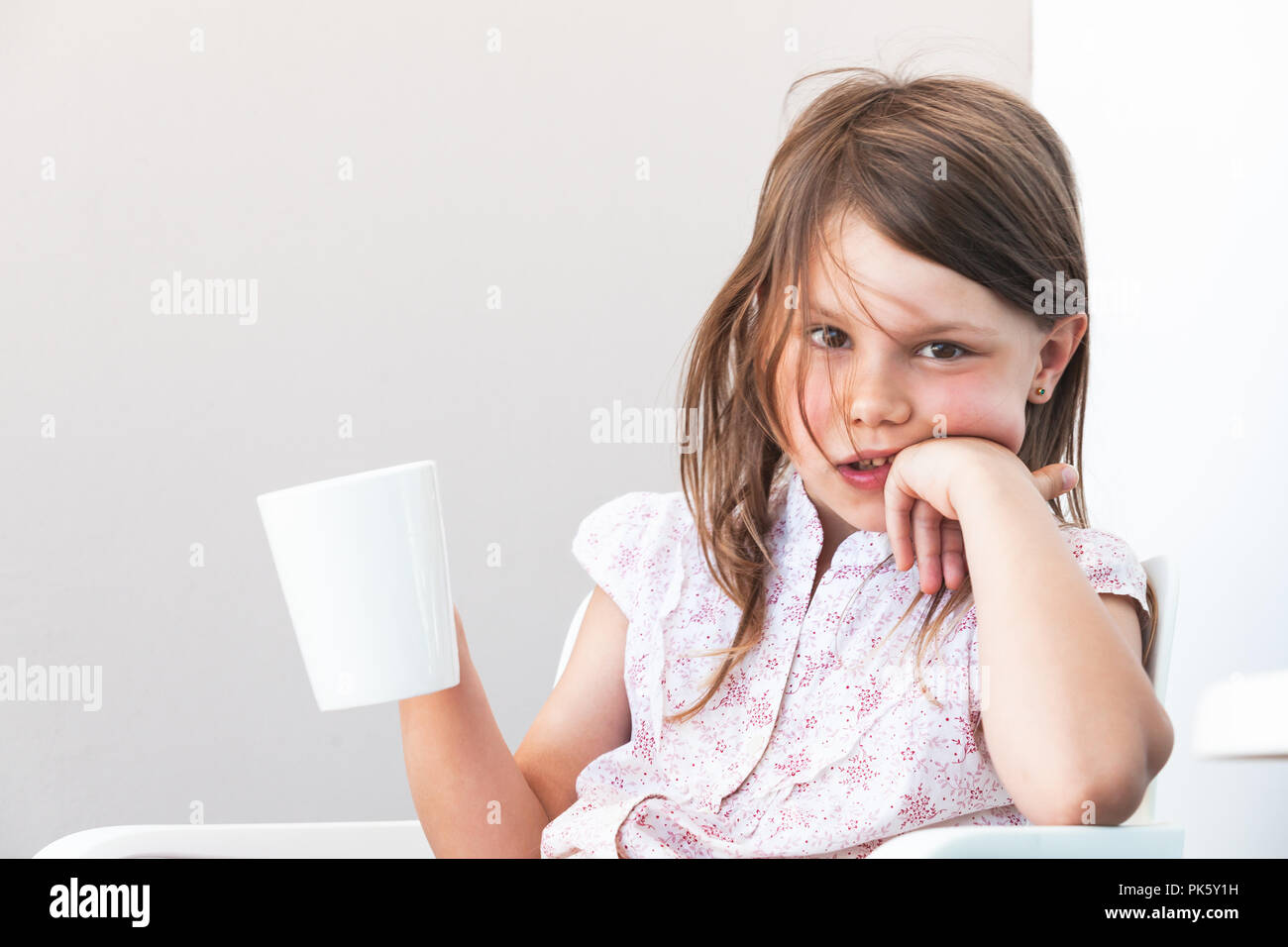 Portrait of little girl with cup of hot chocolate, close-up photo over white wall background Stock Photo
