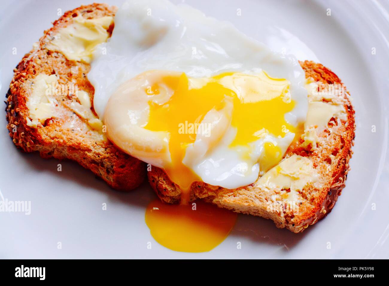 The perfect poached egg served on seeded buttered brown toast Stock Photo