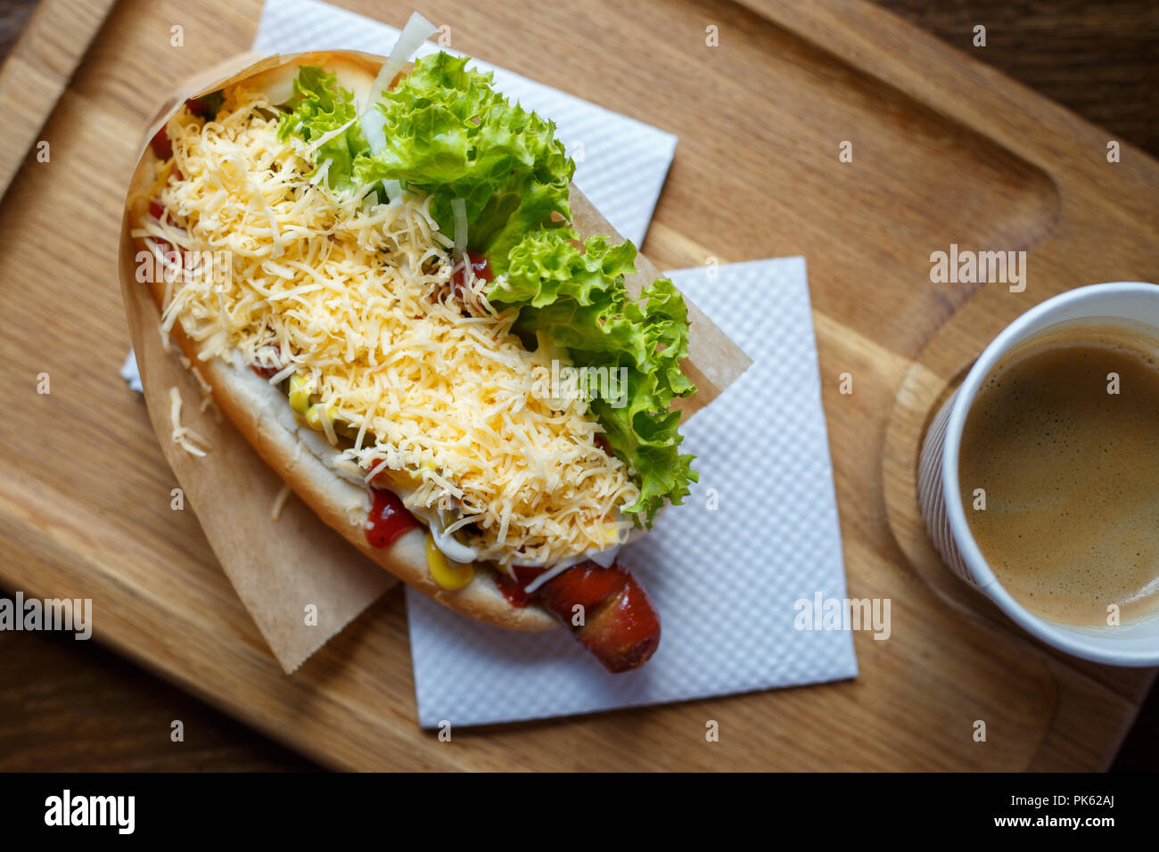 Hot dog with salad and cup of coffee on the table Stock Photo