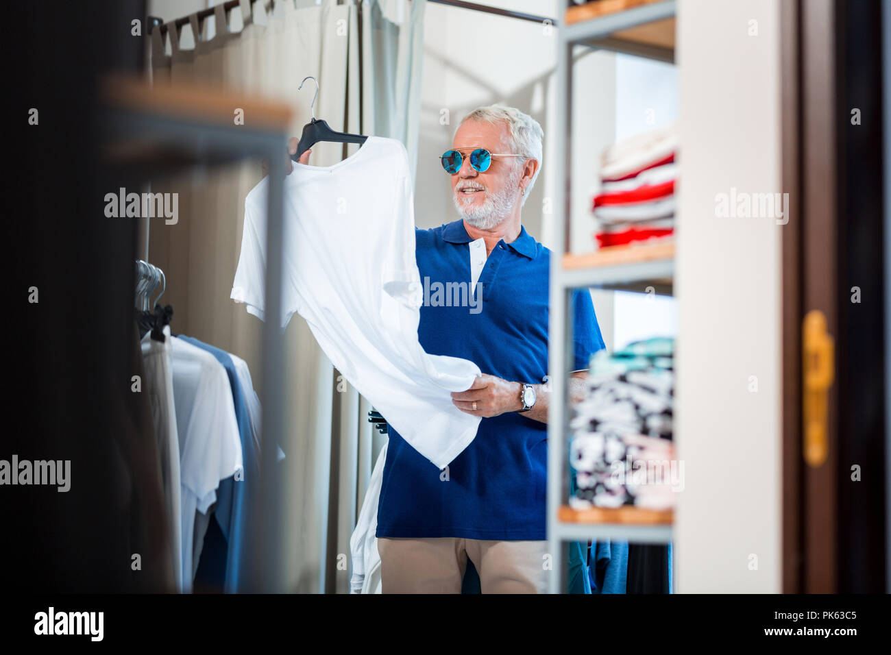 Curious elderly customer scrutinizing a white T-shirt Stock Photo