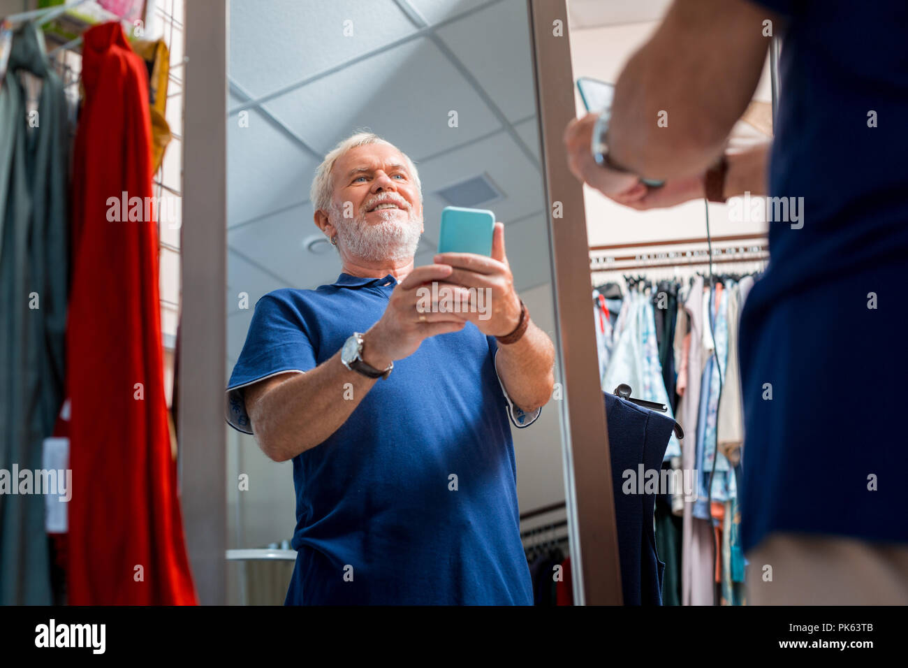 Joyful grey haired man admiring his reflection in shopping store Stock Photo