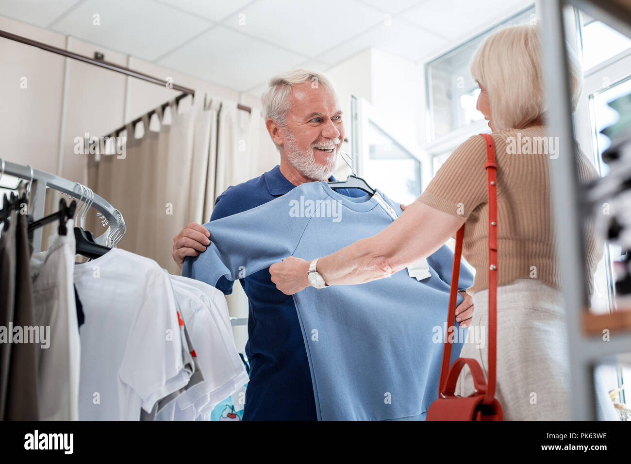 Elderly family choosing a pullover together in clothing store Stock