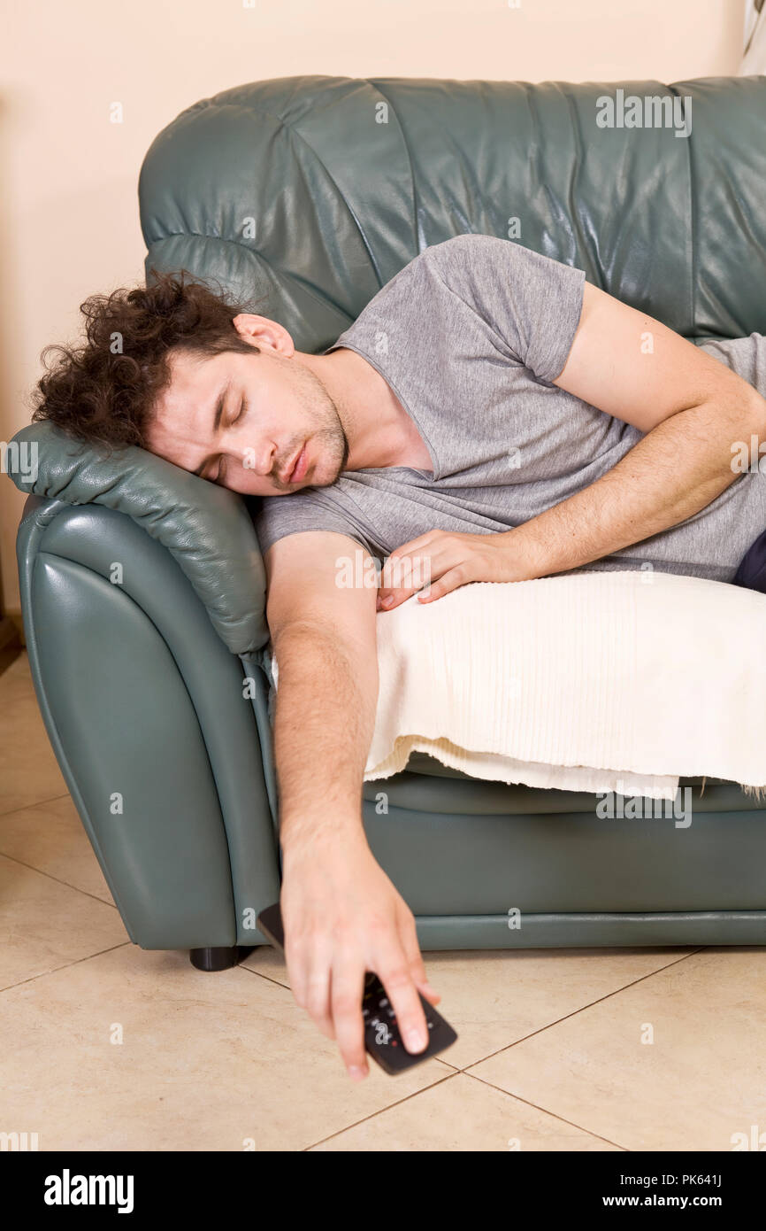 Tired young man sleeping on a sofa Stock Photo