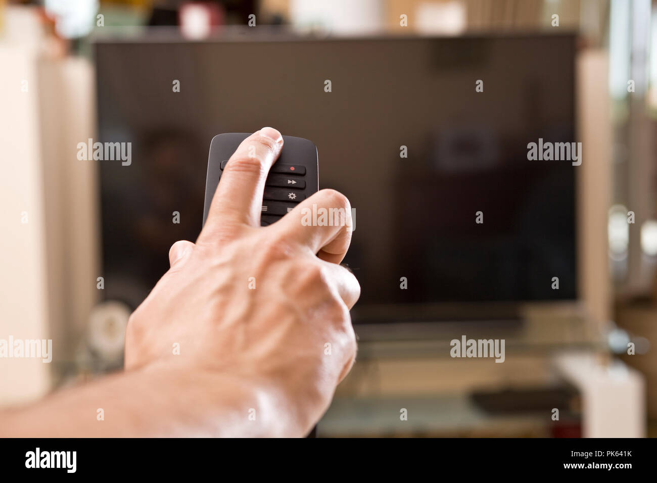 Yong man hand with remote changes channels Stock Photo