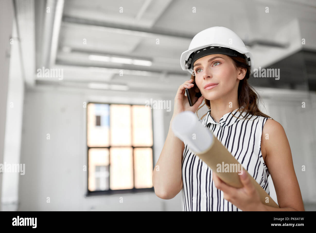 architect with blueprint calling on cell at office Stock Photo