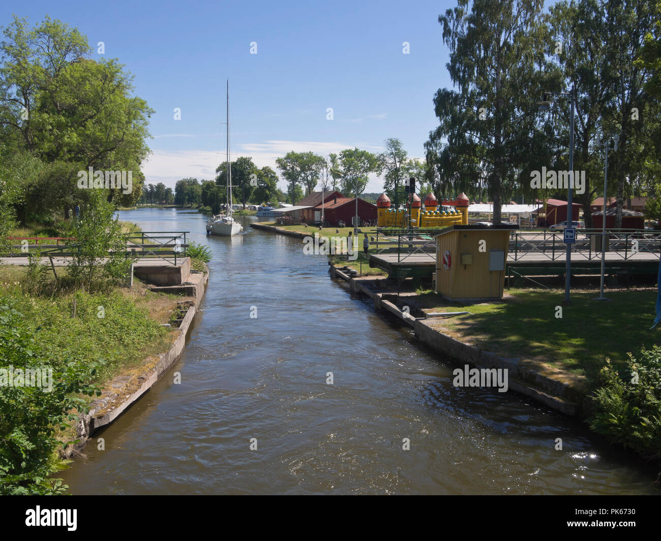 Göta kanal, boat cruise along an idyllic waterway in Sweden, sailboat passing Wassbacken with camping ground, guest harbor and other accommodation Stock Photo