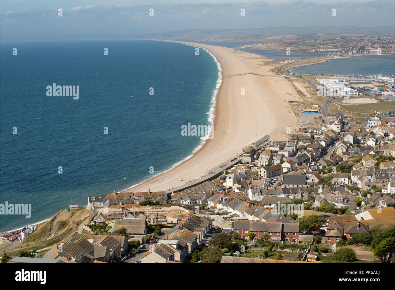 Looking west along Chesil beach from the Isle of Portland on a sunny day  with an onshore wind that has created some surf. Some anglers can be seen  fis Stock Photo 