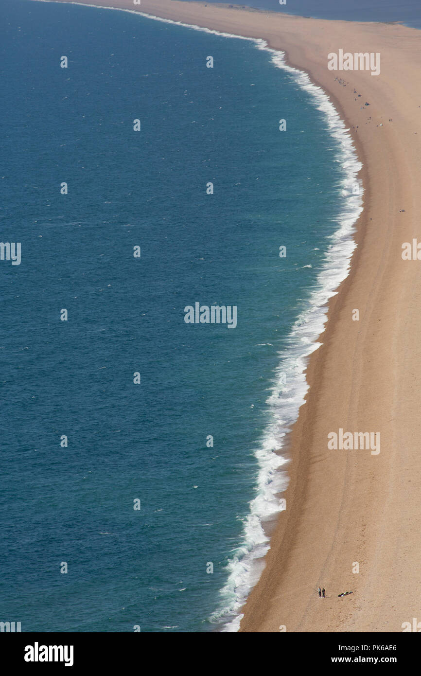 Looking west along Chesil beach from the Isle of Portland on a sunny day  with an onshore wind that has created some surf. Some anglers can be seen  fis Stock Photo 