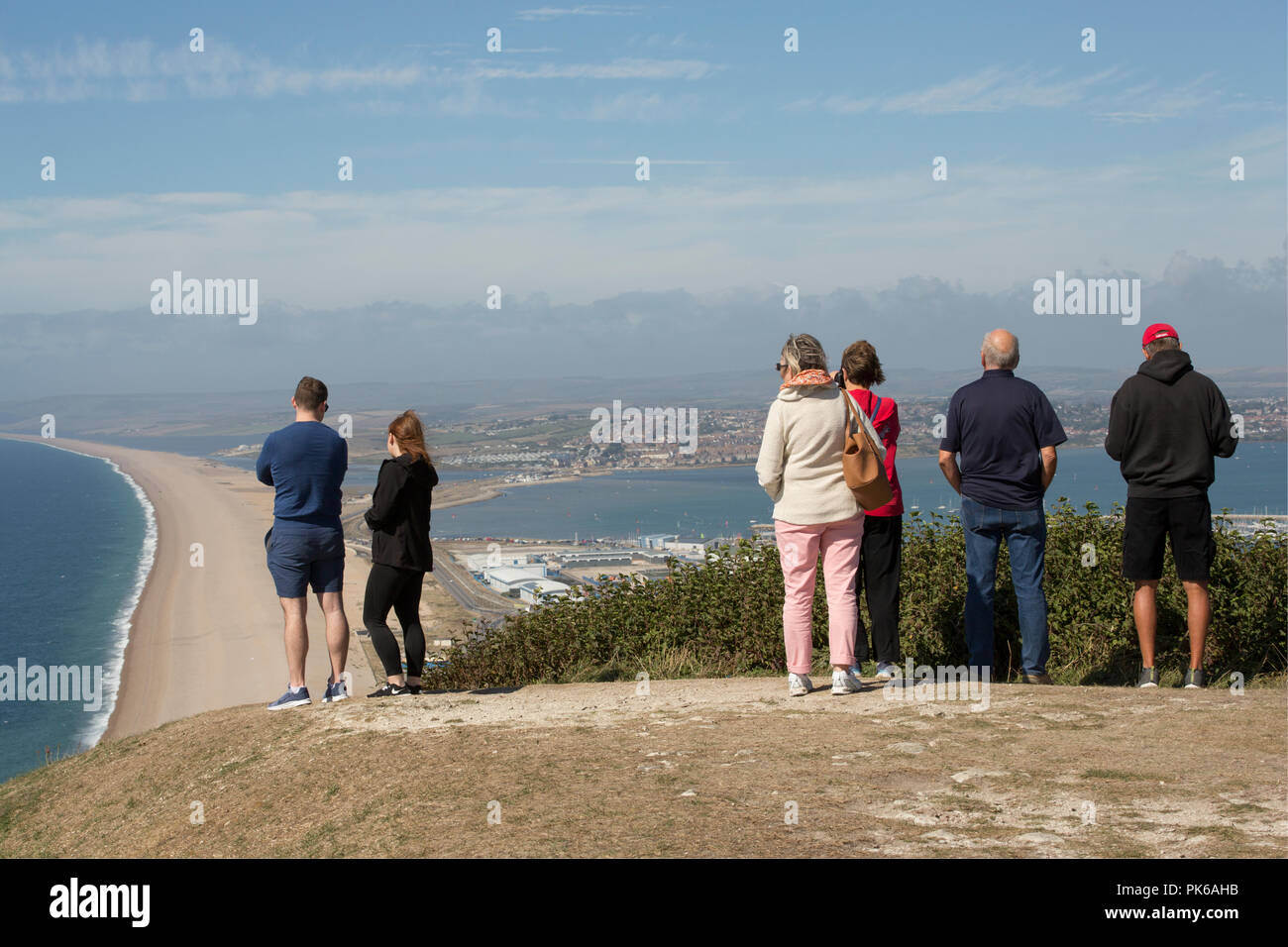 Six people on a sunny day viewing Chesil beach, on the left of the picture, and Portland Harbour, to the right of the picture, from the Isle of Portla Stock Photo