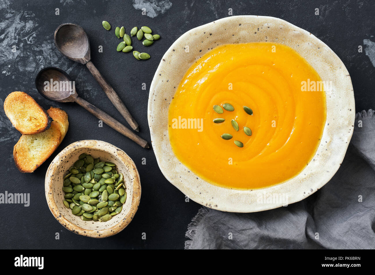 Pumpkin cream soup with toast and seeds on a rustic dark background. Top view, overhead, flat lay. Stock Photo