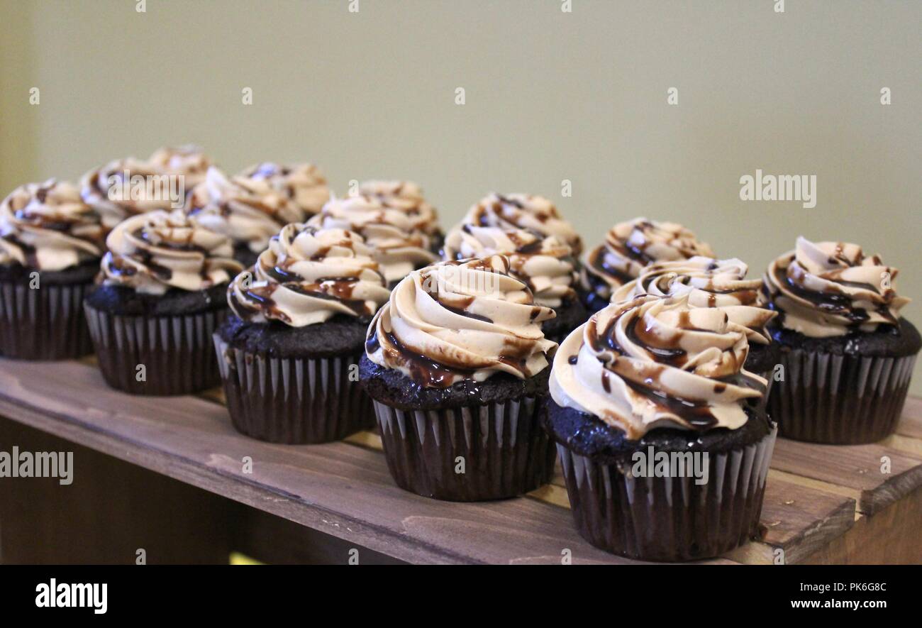 eleven chocolate cupcakes with peanut butter frosting on a wooden table Stock Photo