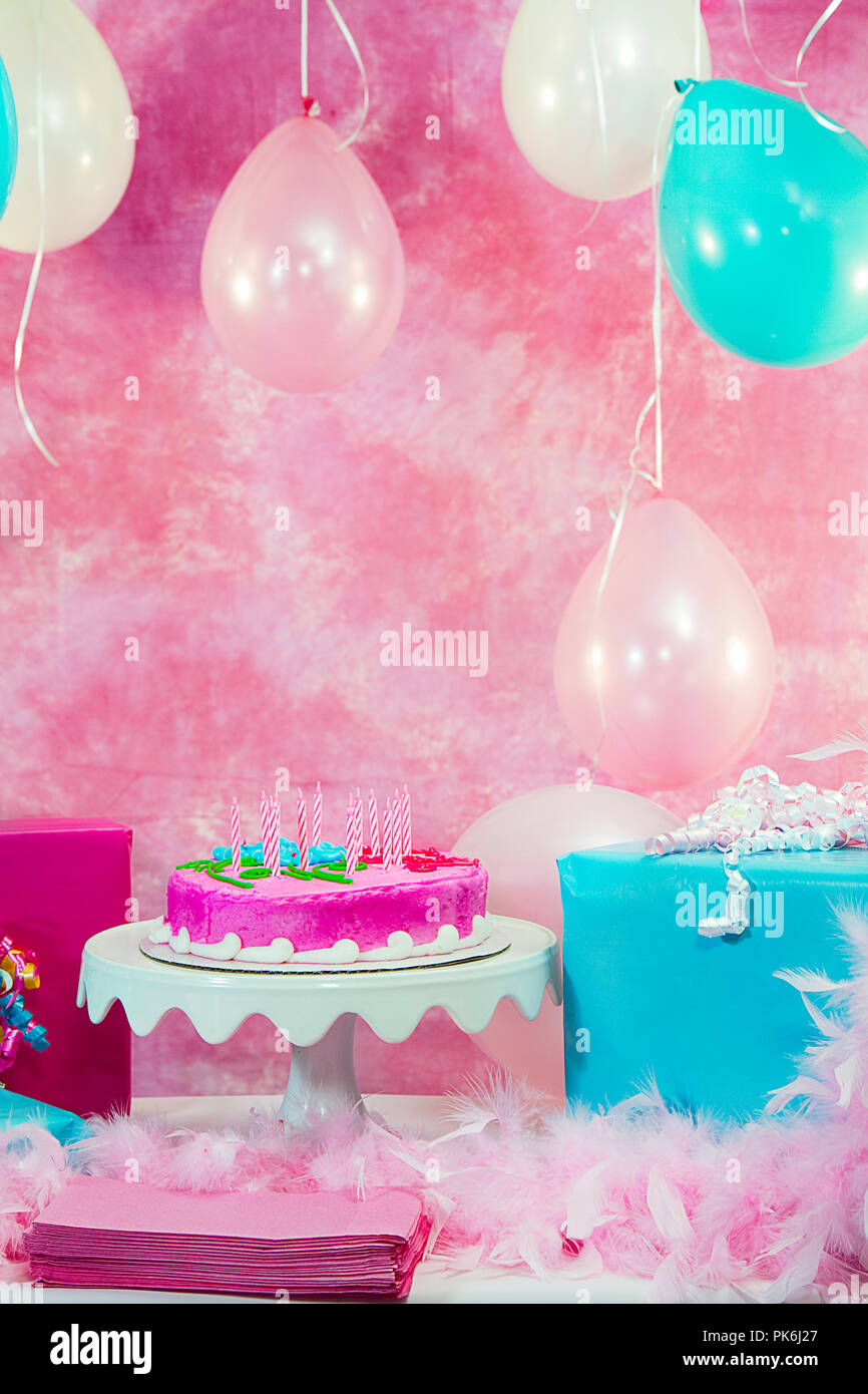 Two beautiful young preteen girls celebrating at a birthday party.  Pink and Aqua balloons and decorations including cake.  Gifts and girls having fun Stock Photo