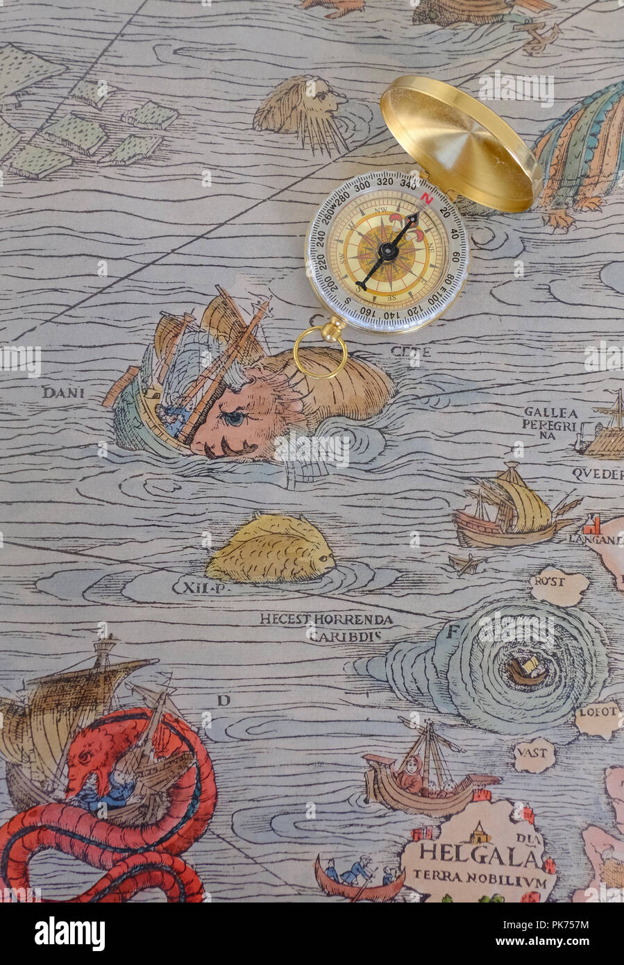 Compass placed on top of reproduction of section of Olaus Magnus's 16th century Marine Map featuring a Prister sinking a ship Stock Photo