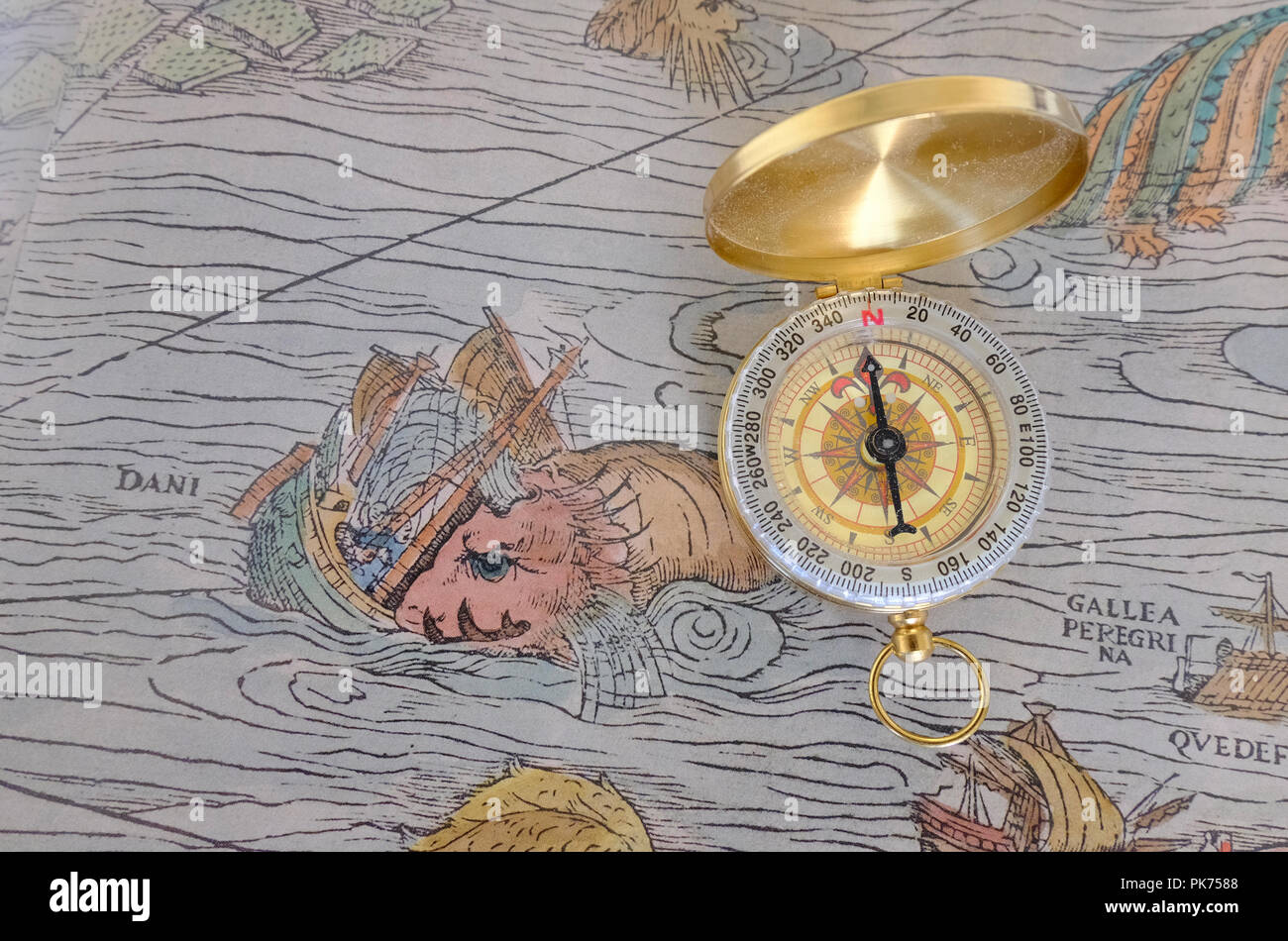 Compass placed on top of reproduction of section of Olaus Magnus's 16th century Marine Map featuring a Prister sinking a ship Stock Photo