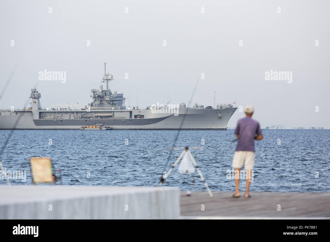 September 10, 2018 - Thessaloniki, Greece - A man fishes at the seafront of the city with the USS Mount Whitney seen at the background. USS Mount Whitney LCC-20 visits the northern Greek city of Thessaloniki during Thessaloniki International Trade Fair 2018, where USA participates as the honoured country this year. (Credit Image: © Giannis Papanikos/ZUMA Wire) Stock Photo