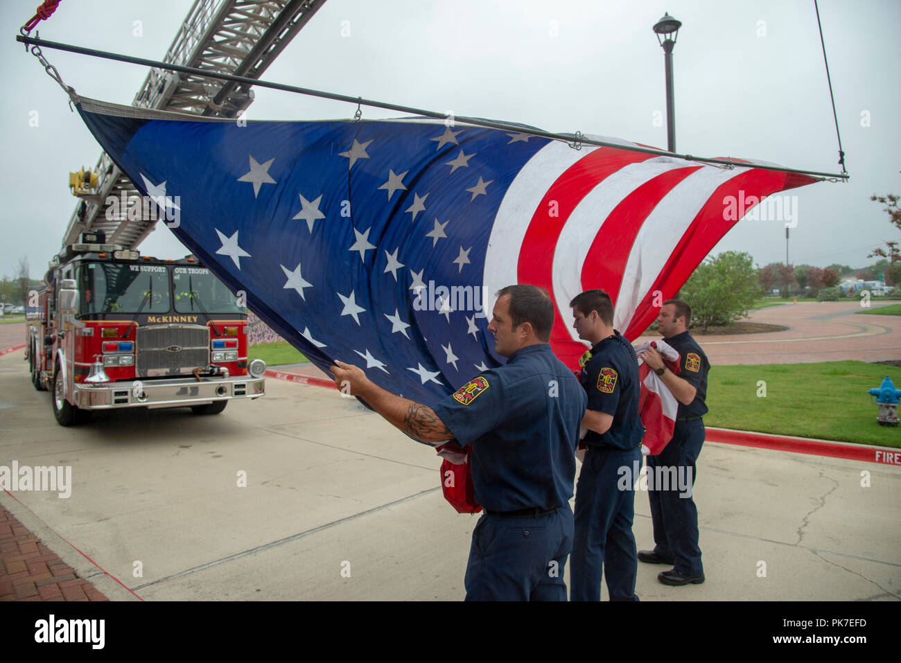 McKinney, USA. September 11: A Day of Remembrance. Firefighters in the city of McKinney, north Texas, prepare to hang a large U.S. flag from the ladder of their fire truck in memorial to those who lost their lives in the September 11, 2001 terrorist attack on the World Trade Center towers in New York City and the Pentagon in Washington D.C. Credit: Nick Young/Alamy Live News Stock Photo