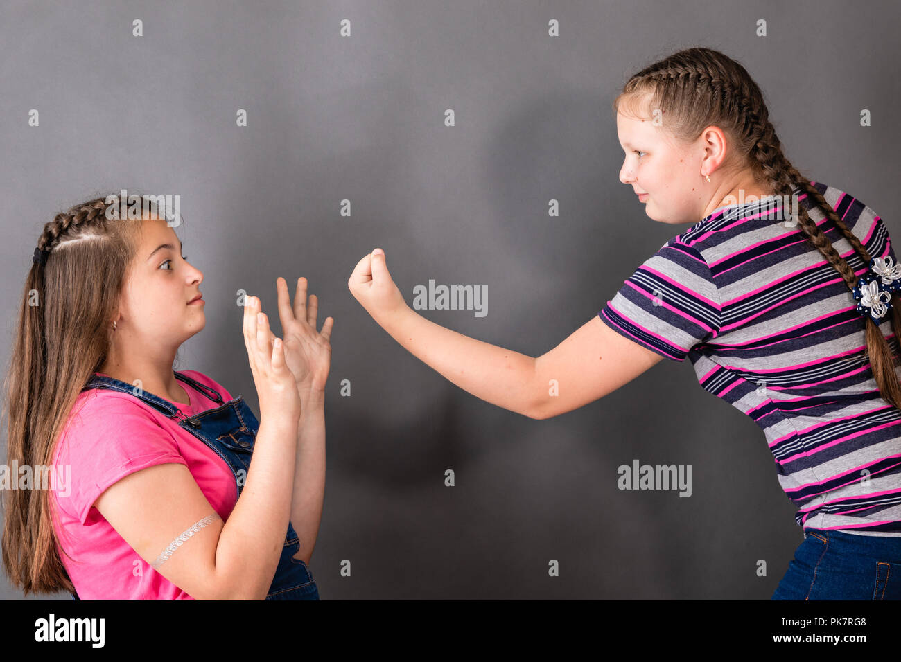 The younger sister frightens the eldest, showing her a fist Stock Photo