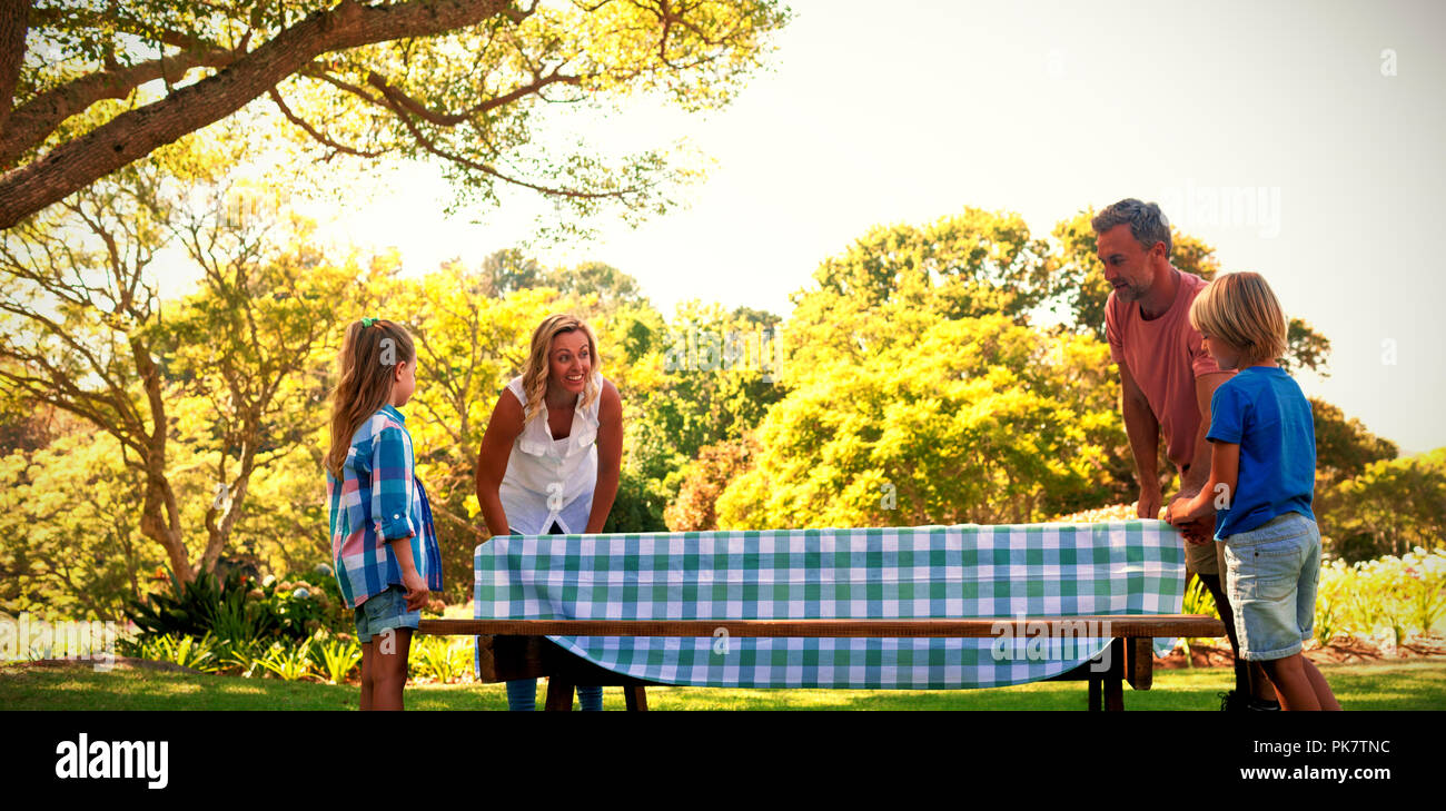 Family spreading the tablecloth on picnic table Stock Photo