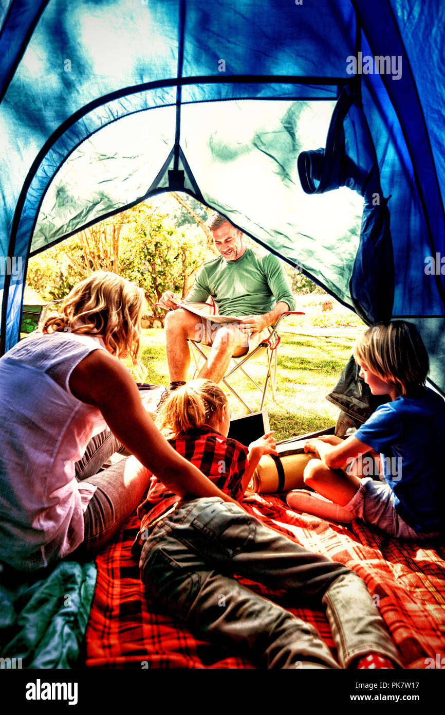 Kids and mother using tablet while father looking at the map Stock Photo