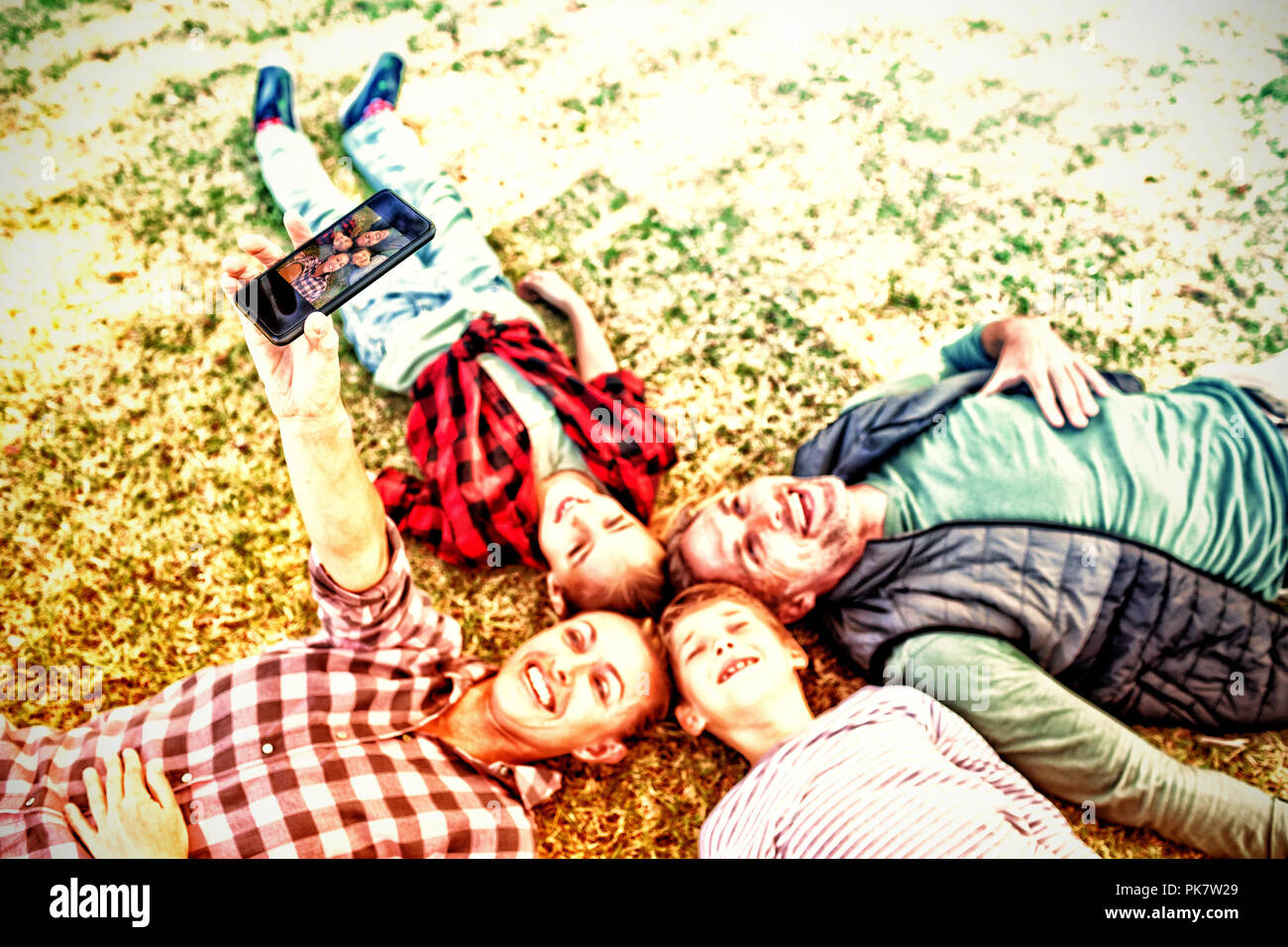 Happy family lying on the grass and taking selfie Stock Photo