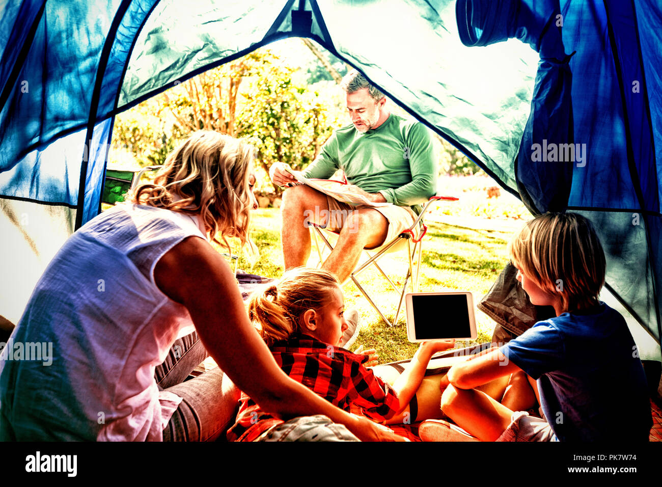 Kids and mother using tablet while father looking at the map Stock Photo