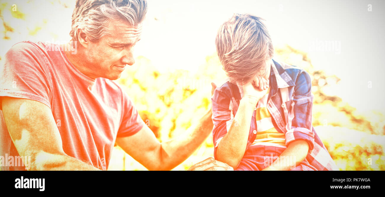 Father consoling his son at picnic in park Stock Photo