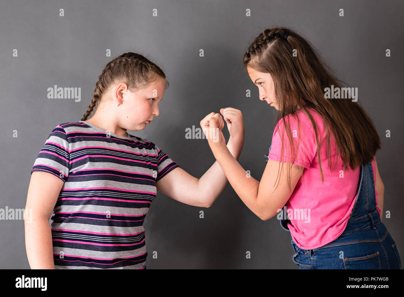 Two sisters quarreling and threatening fists to each other's Stock Photo