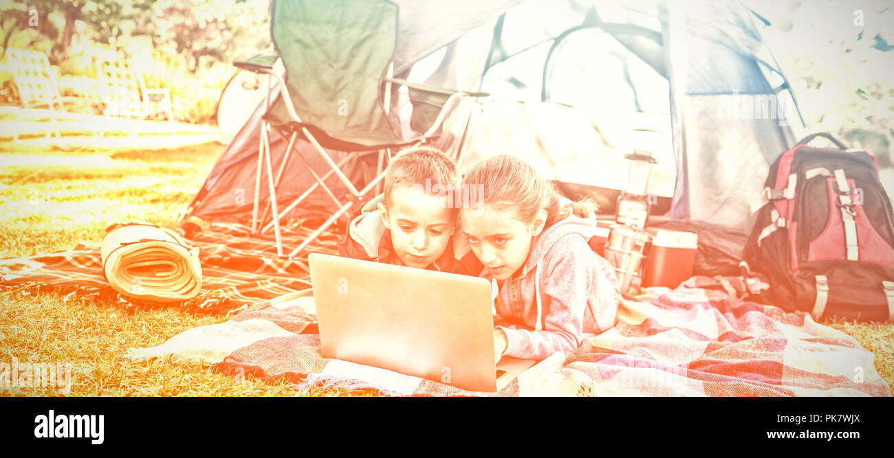 Siblings using laptop outside the tent Stock Photo