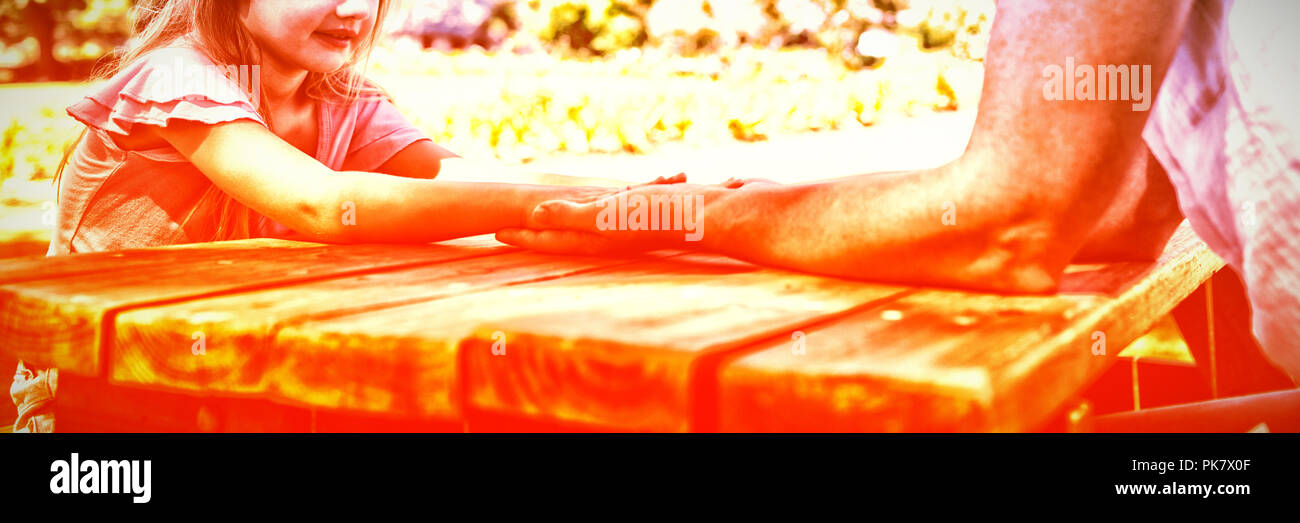 Mother and daughter holding hands on picnic table Stock Photo