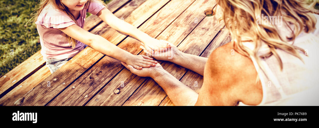 Mother and daughter holding hands on picnic table Stock Photo