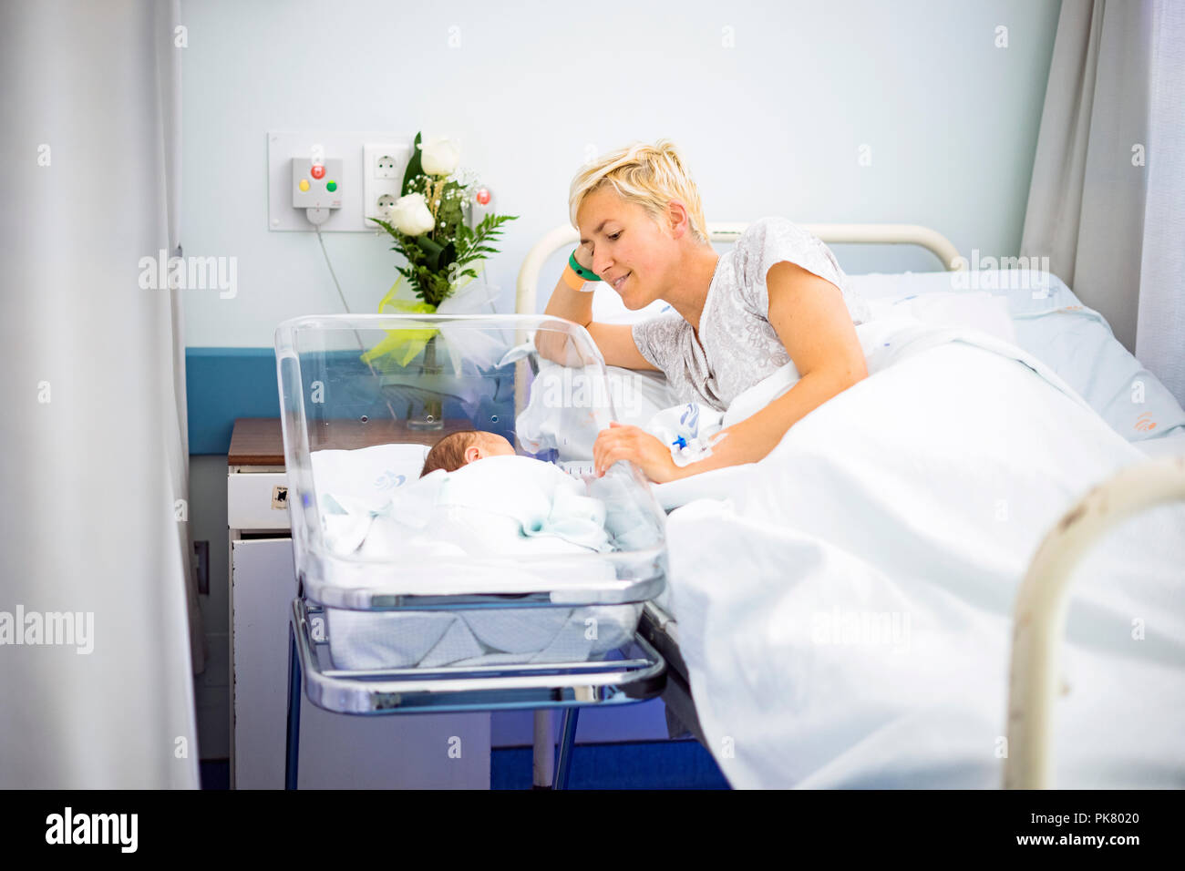 Mother looking with love at her newborn baby boy still in the hospital Stock Photo
