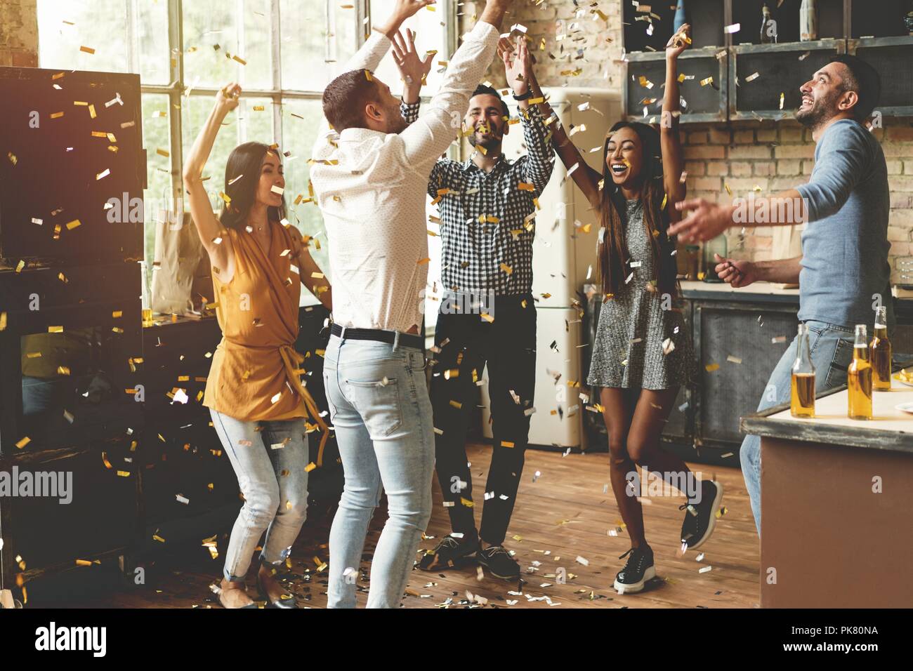 Confetti fun. Group of happy young people throwing confetti and jumping while enjoying home