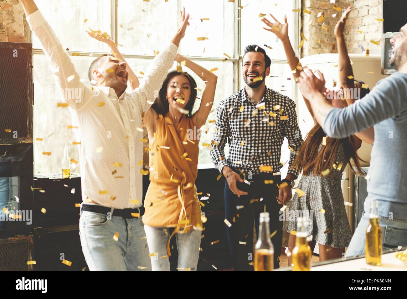 Confetti fun. Group of happy young people throwing confetti and jumping