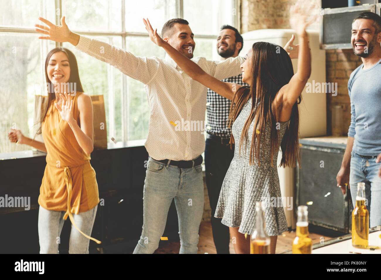 Enjoying party with best friends. Cheerful young people dancing and drinking while enjoying home party on the kitchen. Stock Photo