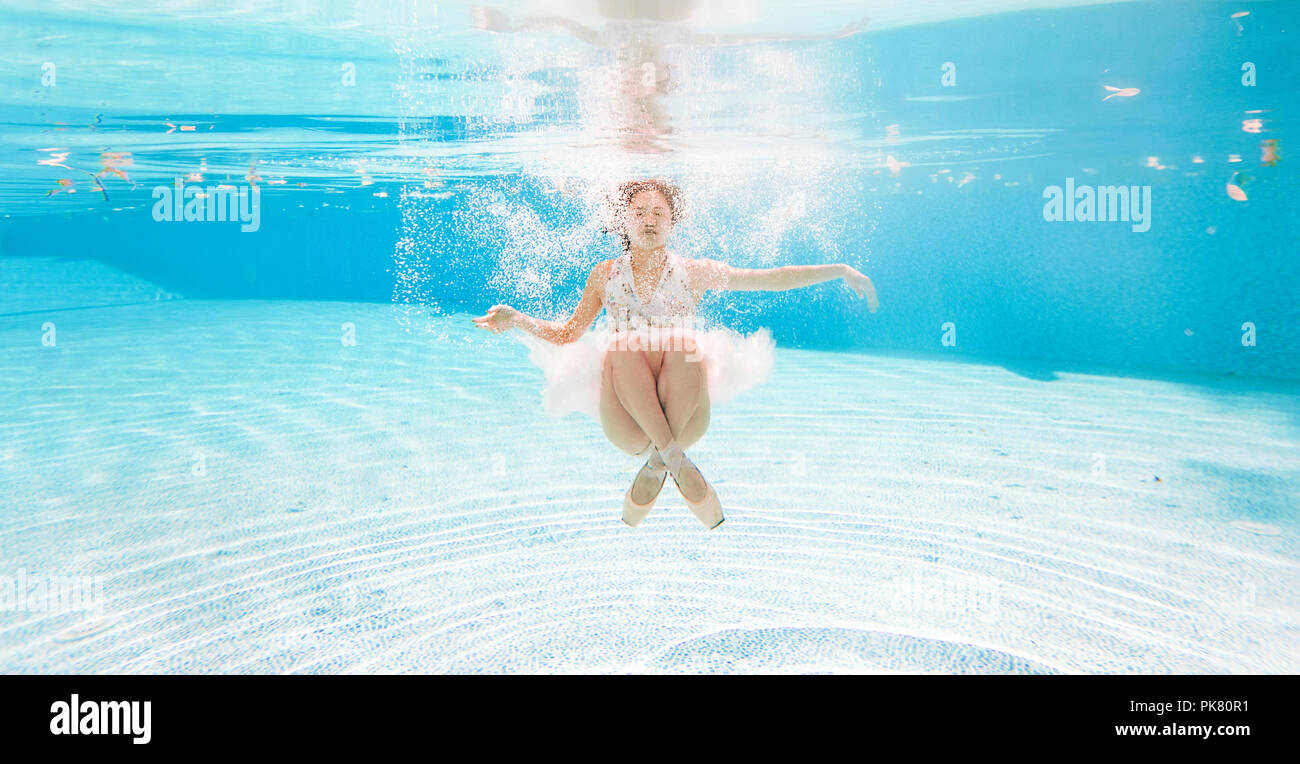 Japanese ballerina is dancing under water on background of air bubbles