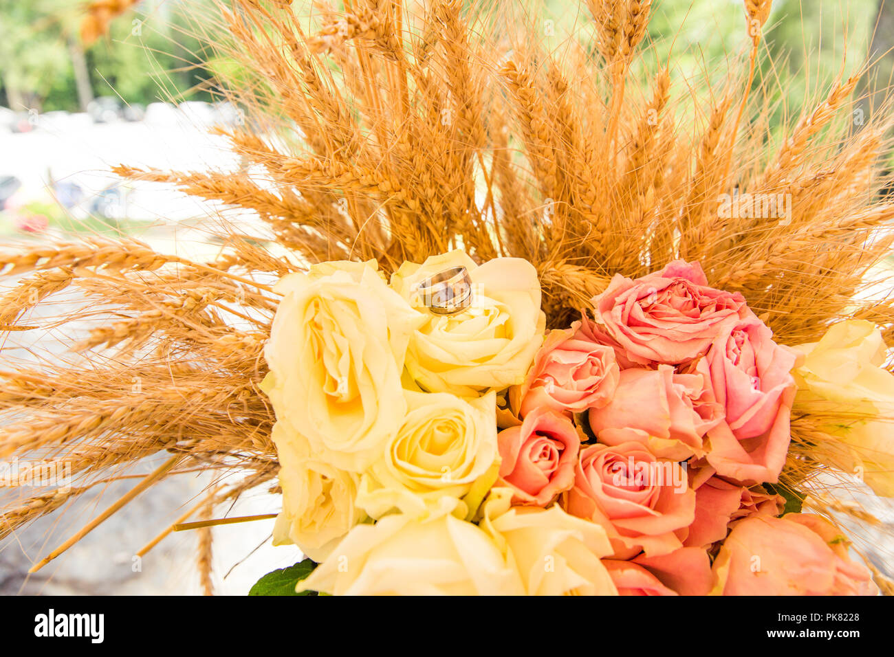 Wedding Rings on Roses Bouquet and Wheat Ears Stock Photo