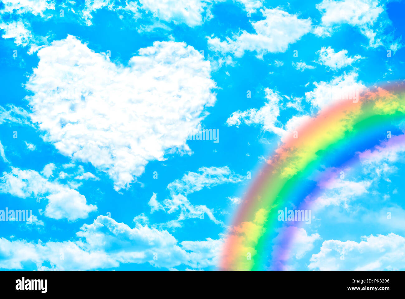 White clouds over blue sky forming “heart” shape with rainbow. Valentine concept. Stock Photo