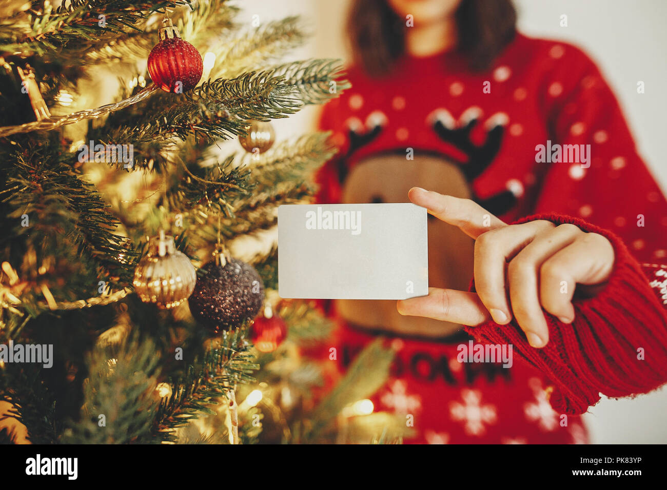hand holding credit card close up on background of golden beautiful christmas tree with lights