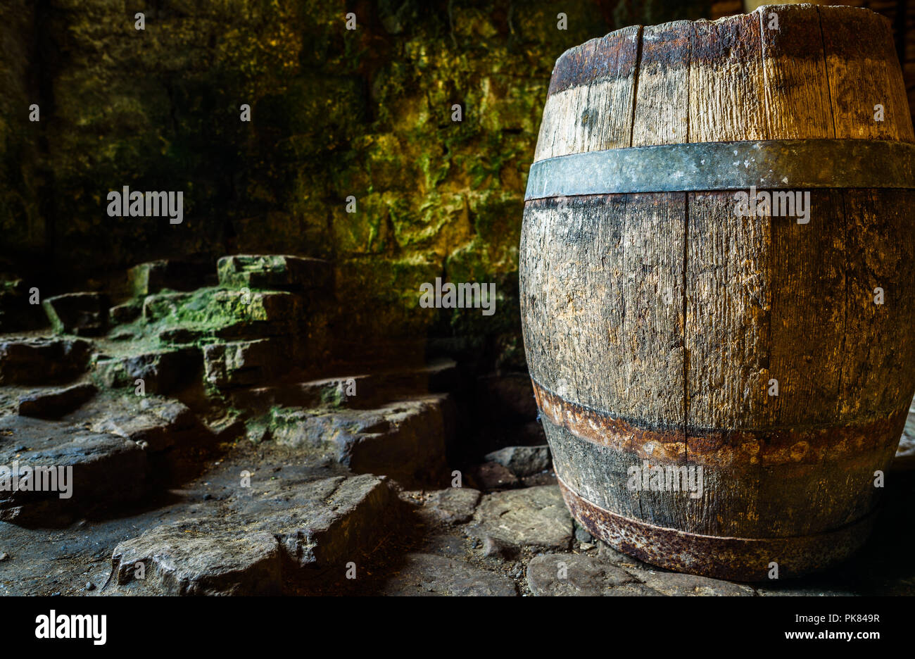 An old oak barrel inside an ancient stone building. Stock Photo