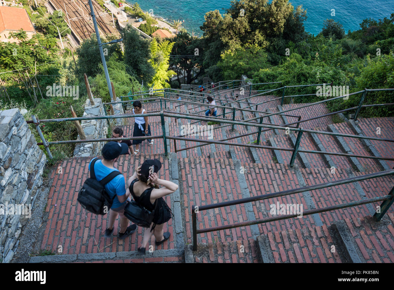 Tourists and local people climbing up and down the steps between train station and Corniglia village, one of Cinque Terre 5 villages, Liguria, Italy Stock Photo