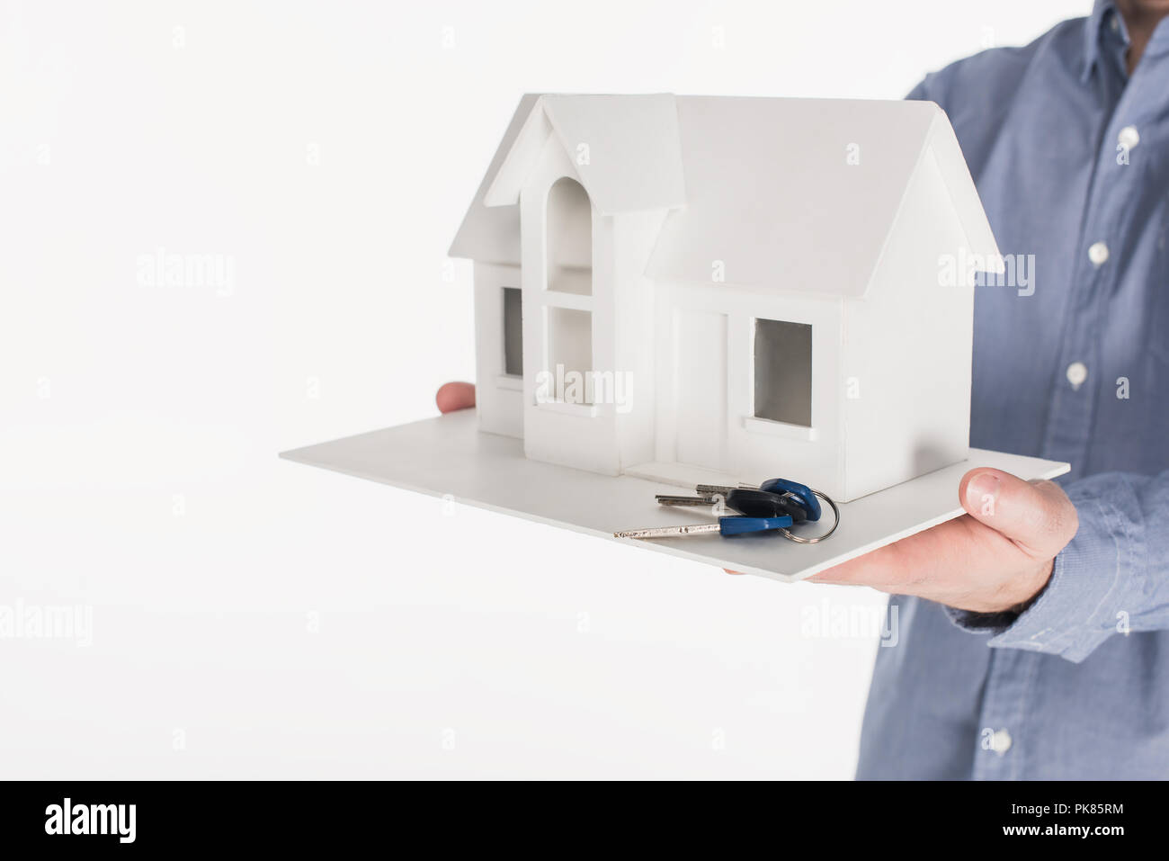 partial view of man holding house model and keys in hands isolated on ...