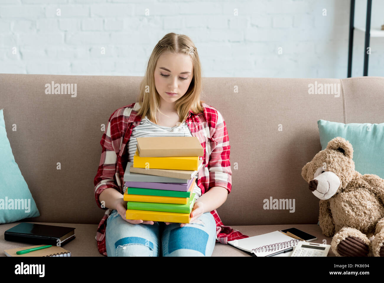 teen student girl with stack of books sitting on couch Stock Photo - Alamy