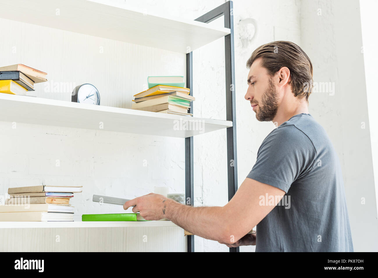 side view of young man putting books on shelves at home Stock Photo Alamy
