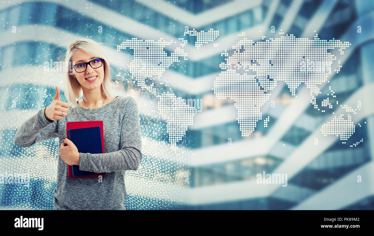 Smiling pretty student girl wearing glasses and holding books show thumb up like gesture over futuristic background with world map. Global modern educ Stock Photo