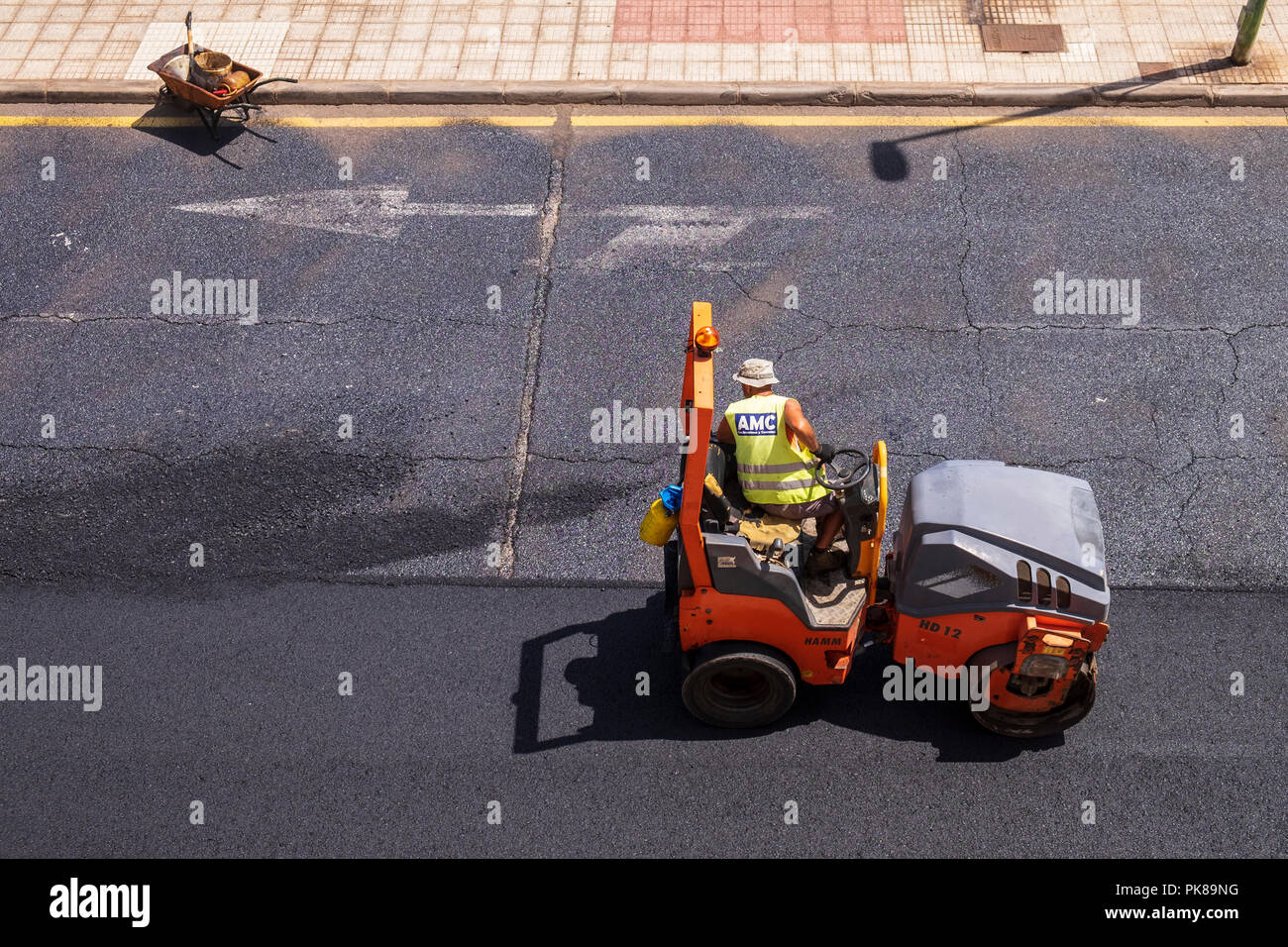 Roller machine smoothing out and compressing a new layer of asphalt during resurfacing of a road Stock Photo