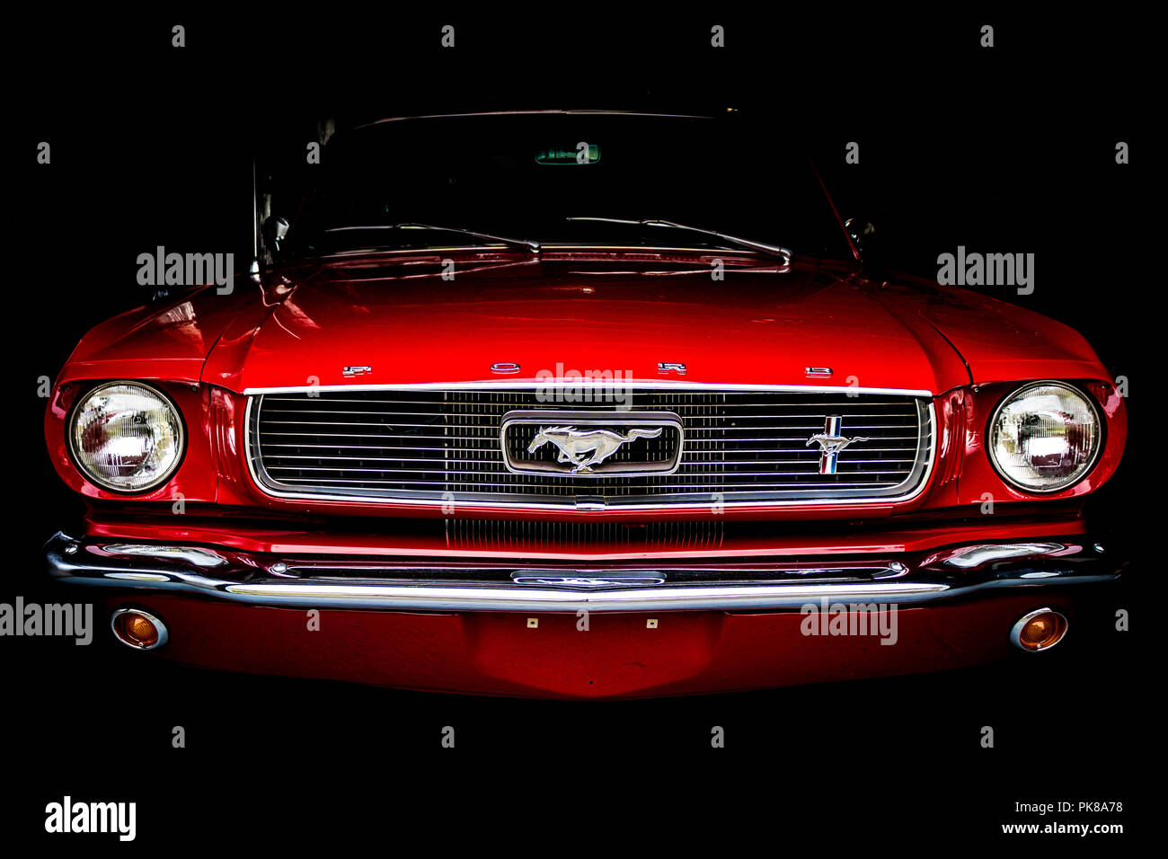 The front end of a 1960s era muscle car juts out from the darkness of a garage. Stock Photo