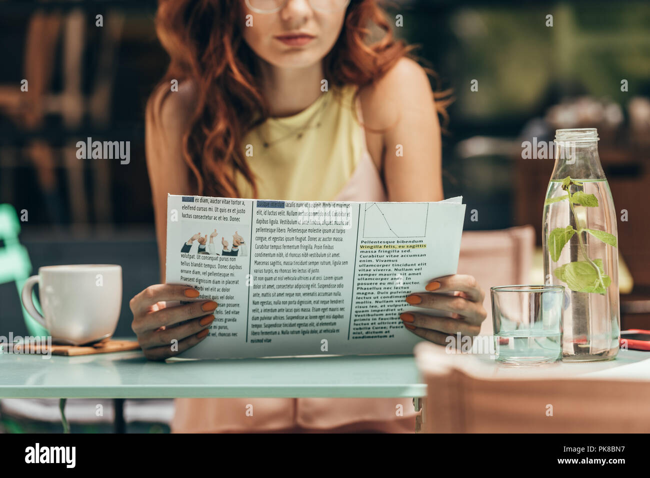 partial view of woman reading newspaper in cafe Stock Photo