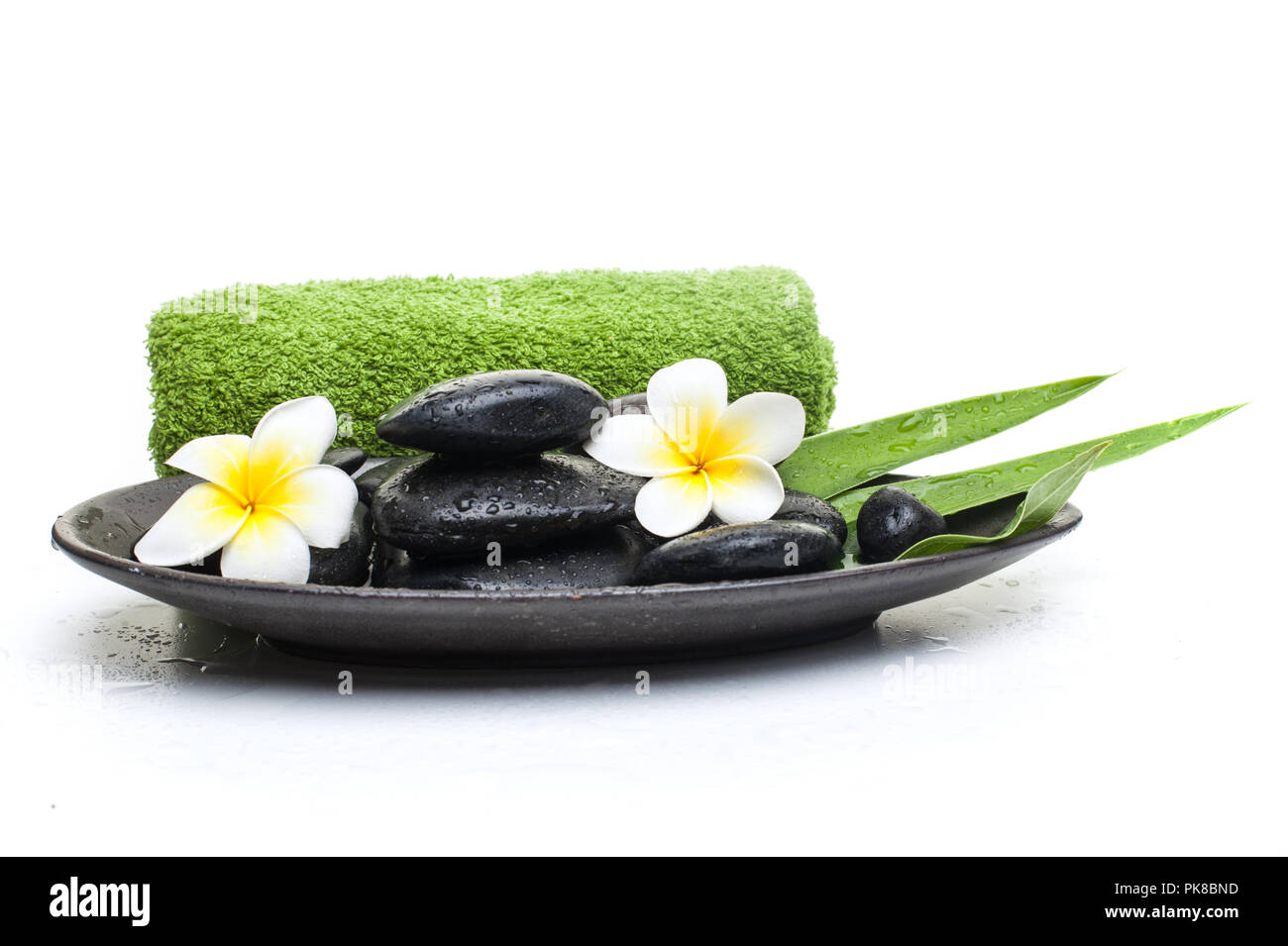 spa flower and black stones with green towel on dark plate Stock Photo